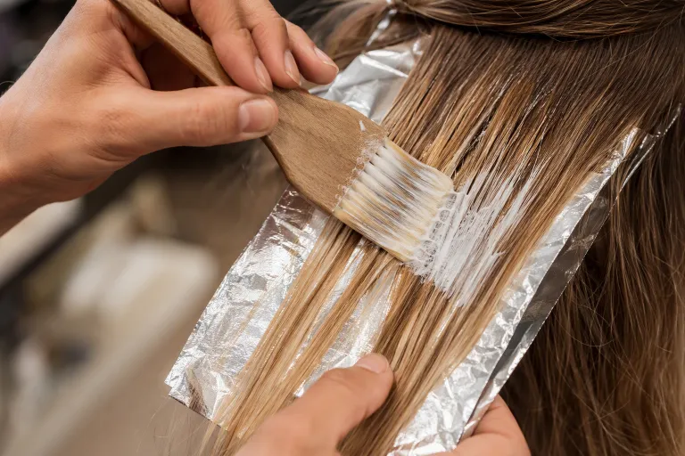 Hands of colorist applying subtle hand-painted balayage highlights in natural light